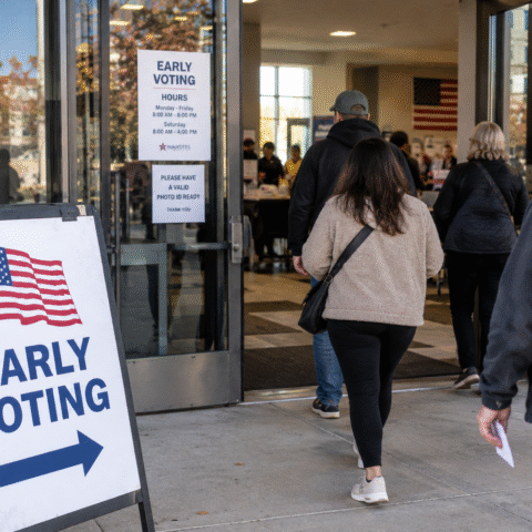 Personas ingresan a un centro de votación anticipada en Estados Unidos, junto a un letrero de Early Voting.
